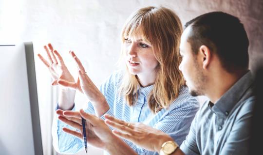 Two business colleagues problem-solving at a computer together in the office.